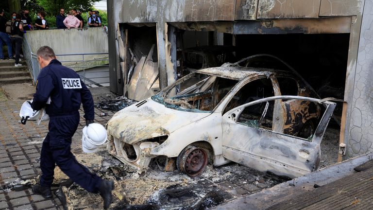 French police stand next to municipal police cars, burnt during night clashes between protesters and police, following the death of Nahel, a 17-year-old teenager killed by a French police officer in Nanterre during a traffic stop, at a police station in Mons-en-Baroeul, near Lille, northern France, June 29, 2023. REUTERS/Pascal Rossignol
