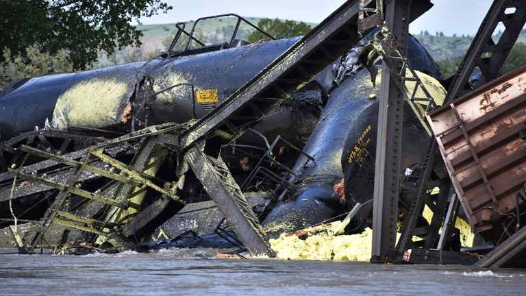 Several train cars are immersed in the Yellowstone River after a bridge collapse near Columbus, Mont., on Saturday, June 24, 2023.   The bridge collapsed overnight, causing a train that was traveling over it to plunge into the water below. (AP Photo/Matthew Brown)