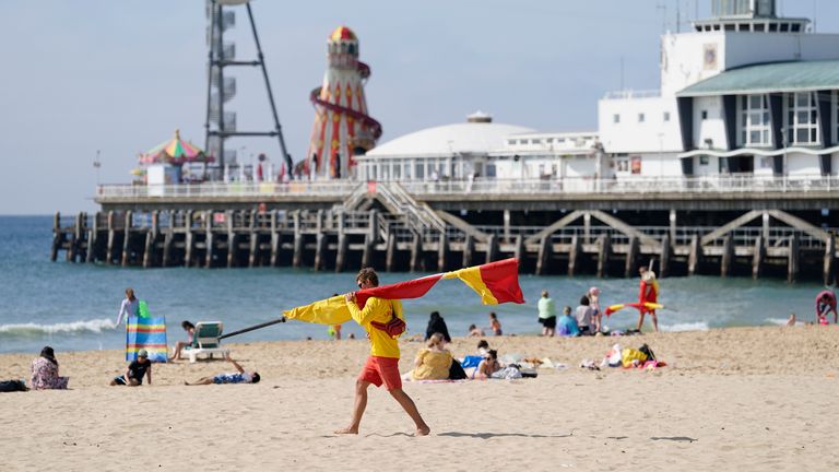 A RNLI lifeguard carrying a flag on Bournemouth beach after a 17-year-old-boy and a girl aged 12 sustained "critical injuries" on Wednesday, and later died in hospital. A man in his 40s has been arrested on suspicion of manslaughter following the incident. Picture date: Thursday June 1, 2023.