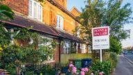 An estate agent for sale sign in the front garden of a house in Oxford, with cars parked on the street in the distance. Pic: iStock