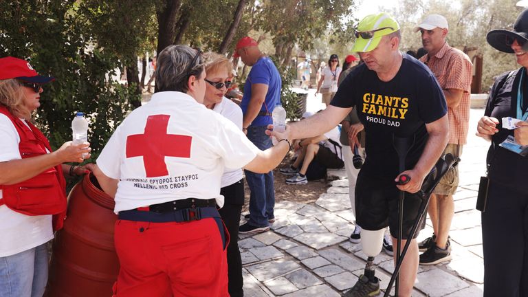 A volunteer gives water to a visitor near the Acropolis hill, during a heatwave in Athens, Greece, July 14, 2023. REUTERS/Louiza Vradi
