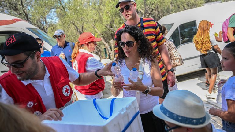 Greek Red Cross workers distribute water bottles to visitors in front of the Acropolis
Pic:AP