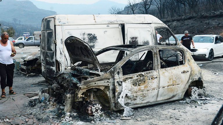 People inspect burnt vehicles after wildfires, in Bouira, 100 km from Algiers, Algeria 
Pic:AP