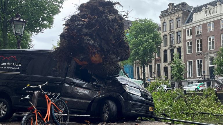 A fallen tree lies on a van after a storm hit Amsterdam
