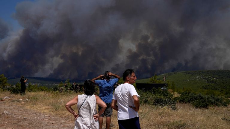 Residents watch as a wildfire burns on a hill in Pournari village near Athens, on Tuesday, July 18, 2023. In Greece, where a second heatwave is expected to hit Thursday, three large wildfires burned outside Athens for a second day. Thousands of people evacuated from coastal areas south of the capital returned to their homes Tuesday when a fire finally receded after they spent the night on beaches, hotels and public facilities. (AP Photo/Thanassis Stavrakis)