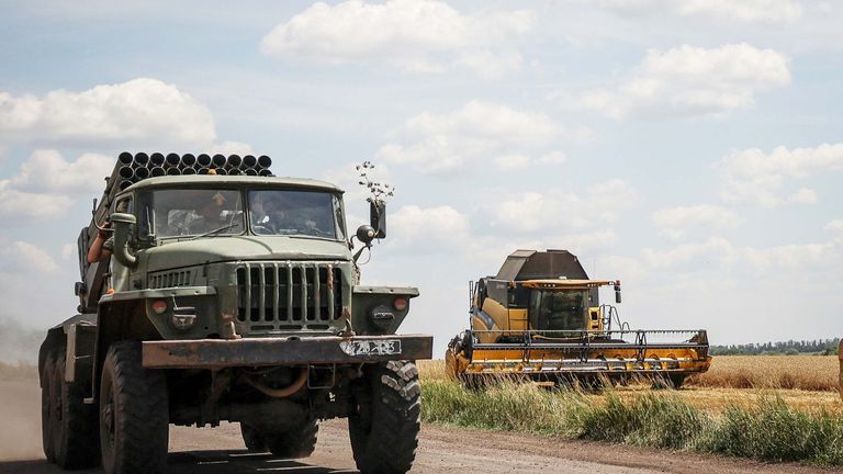 A BM-21 Grad multiple launch rocket system is seen as a combine harvests wheat in Ukraine