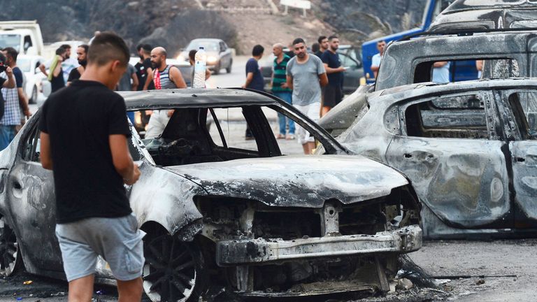 People inspect burnt vehicles after raging wildfires in Bouira, 100 km from Algiers, Algeria 
Pic:AP