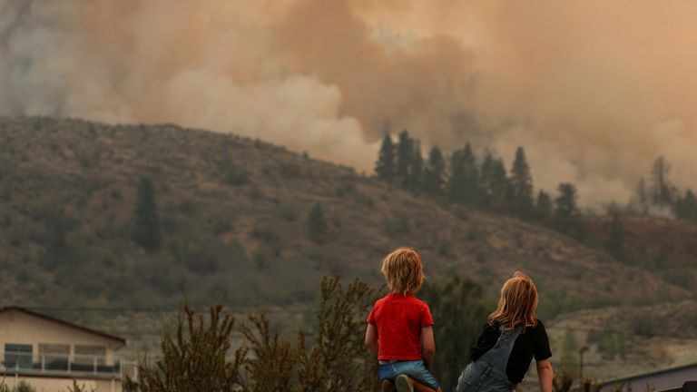Locals gather to watch firefighting efforts amid heavy smoke from the Eagle Bluff wildfire, after it crossed the Canada-U.S. border from the state of Washington and prompted evacuation orders, in Osoyoos, British Columbia, Canada July 30, 2023. REUTERS/Jesse Winter TPX IMAGES OF THE DAY