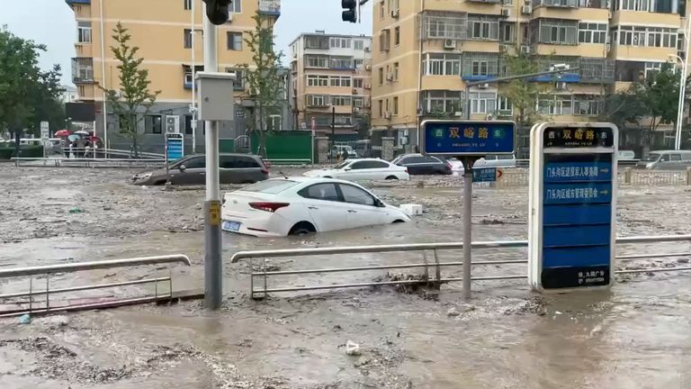 Cars are partially submerged as water gushes on a flooded street, after Typhoon Doksuri made landfall and brought heavy rainfall, at the Mentougou district, in Beijing, China 
