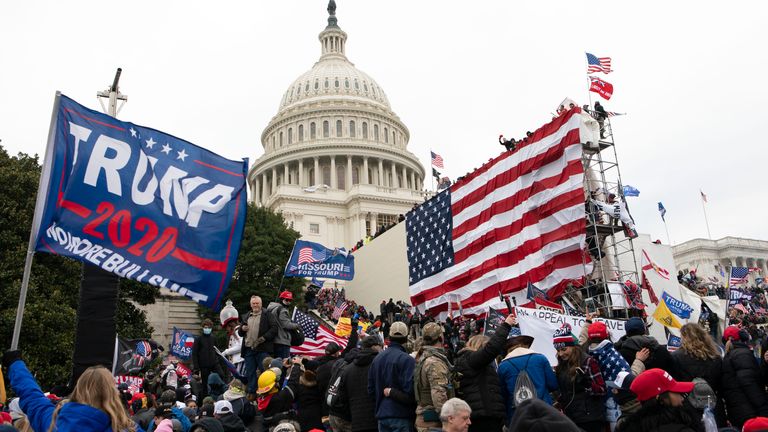 FILE - Rioters stand outside the U.S. Capitol in Washington, on Jan. 6, 2021. A new poll shows that about half of Americans say former President Donald Trump should be charged with a crime for his role in what happened on Jan. 6. The Associated Press-NORC Center for Public Affairs Research poll found that 48% of U.S. adults believe Trump should be held accountable for what happened during the deadly Capitol attack.(AP Photo/Jose Luis Magana, File)