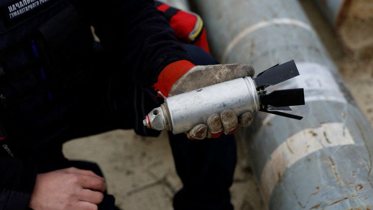 A Ukrainian serviceman with a defused cluster bomb from a Russian missile