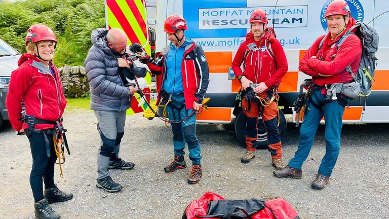 Handout photo issued by the Moffat Mountain Rescue Team of team members reuniting a Jack Russell dog they rescued with its owner (second left) after it plunged 60 metres down the Grey Mare&#39;s Tail waterfall in Dumfries and Galloway at around 2.45pm on Sunday. Picture date: Sunday July 16, 2023.