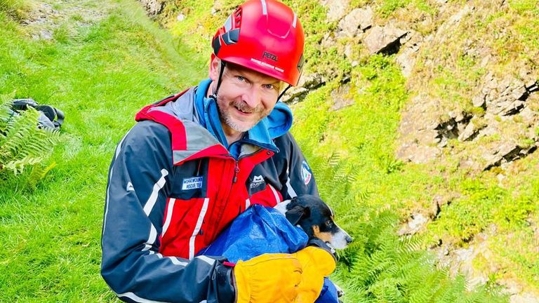 Handout photo issued by the Moffat Mountain Rescue Team of a team member with a Jack Russell dog they rescued after it plunged 60 metres down the Grey Mare&#39;s Tail waterfall in Dumfries and Galloway at around 2.45pm on Sunday. Picture date: Sunday July 16, 2023.
