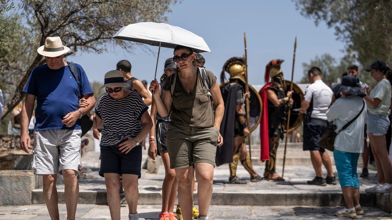 Tourists exit the ancient Acropolis of Athens as the Greek culture ministry shut down the monument most of the day because of heat, Friday, July 14, 2023. Temperatures were starting to creep up in Greece, where a heatwave was forecast to reach up to 44 degrees Celsius in some parts of the country over the weekend. (AP Photo/Petros Giannakouris)