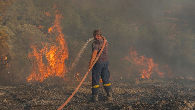 Firefighter Nektarios Kefalas tries to extinguish a wildfire burning near the village of Asklipieio, on the island of Rhodes, Greece, July 24, 2023. REUTERS/Nicolas Economou
