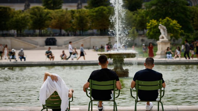 People sit by a fountain in the Tuileries gardens, Monday, July 10, 2023 in Paris where temperatures are expected to rise up to 30 degrees Celsius (86 degrees Fahrenheit). (AP Photo/Thomas Padilla)