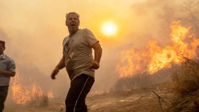 A local reacts as the flames burn trees in Gennadi village, on the Aegean Sea island of Rhodes, southeastern Greece 
Pic:AP