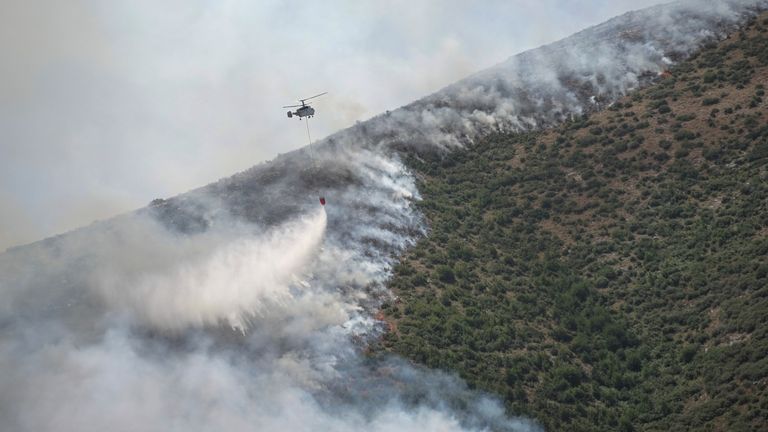 A firefighting helicopter drops water as wildfire burns near the village of Palia Perithia, on the island of Corfu, Greece 