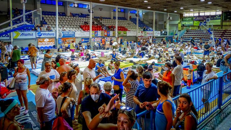 Evacuees sit inside a stadium following their evacuation during a forest fire on the island of Rhodes