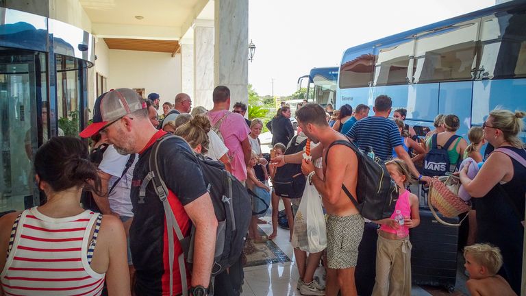 Evacuees wait to board on buses as they leave their hotel during a forest fire on the island of Rhodes