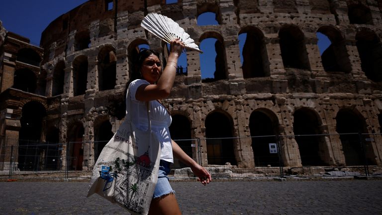 Michelle from the U.S. uses a fan to shelter from the sun near the Colosseum during a heatwave across Italy, in Rome, Italy July 11, 2023. REUTERS/Guglielmo Mangiapne