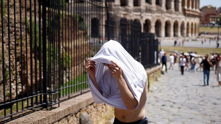 A man shelters from the sun with a t-shirt near the Colosseum during a heatwave across Italy, in Rome, Italy July 11, 2023. REUTERS/Guglielmo Mangiapne