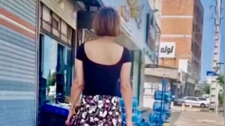 A woman walks down a street in Iran with her hair uncovered