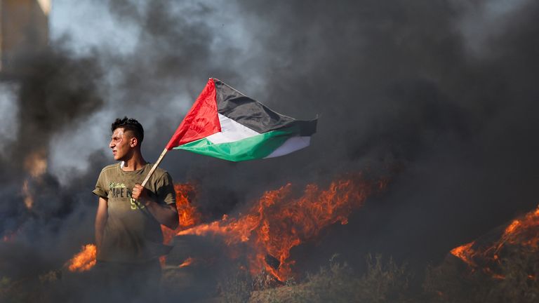 A Palestinian holds a flag as he takes part in a protest against Israeli army raid in Jenin, along Israel-Gaza border fence east of Gaza City July 3, 2023. REUTERS/Mohammed Salem
