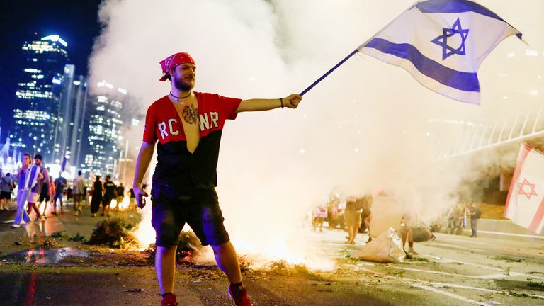 A protester holds an Israeli flag during a demonstration against Israeli Prime Minister Benjamin Netanyahu and his nationalist coalition government&#39;s judicial overhaul, in Tel Aviv, Israel July 20, 2023. REUTERS/Corinna Kern