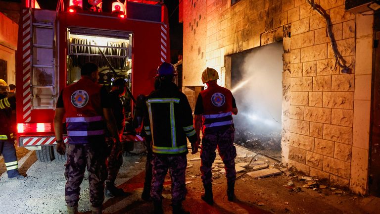 Emergency workers spray water into a damaged building as Israeli troops start withdrawing from Jenin