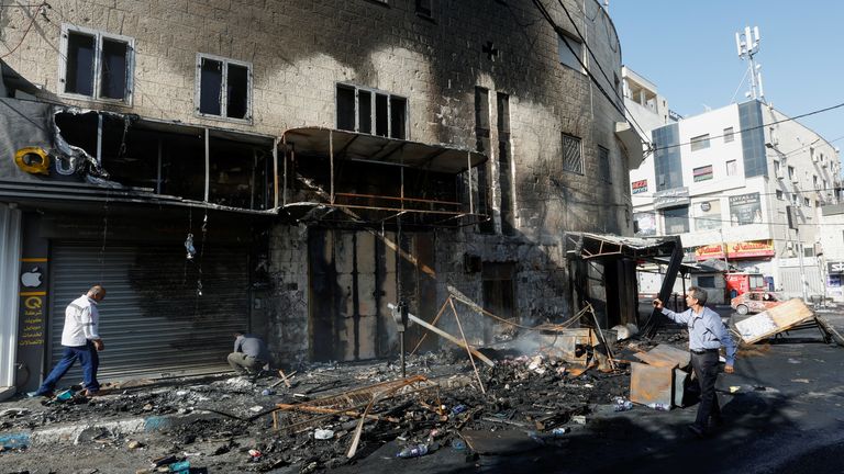 People walk past debris and a building damaged amid an Israeli military operation, in Jenin, in the Israeli-occupied West Bank July 4, 2023. REUTERS/Mohamad Torokman