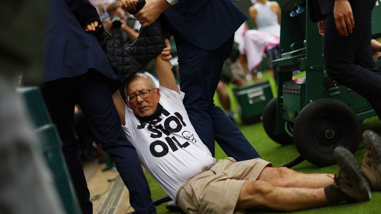 A Just Stop Oil protester is detained by security staff on court 18 during the first round match between Britain's Katie Boulter and Australia's Daria Saville