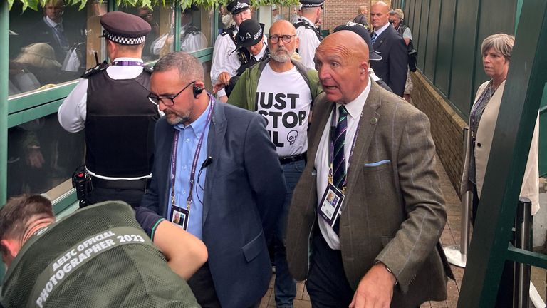 Just Stop Oil protesters are escorted away by Police after throwing orange confetti on court 18 on day three of the 2023 Wimbledon Championships at the All England Lawn Tennis and Croquet Club in Wimbledon. Picture date: Wednesday July 5, 2023.