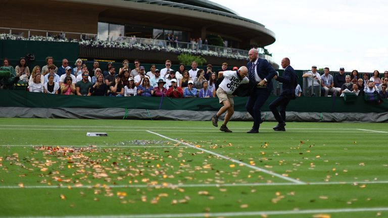 A Just Stop Oil protester is detained by security staff on court 18 during the first round match between Britain's Katie Boulter and Australia's Daria Saville  
