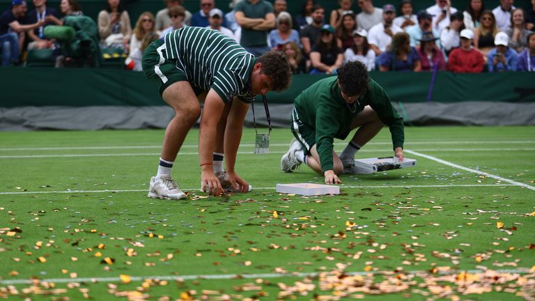 Ball boys help to pick up confetti thrown by a Just Stop Oil protester on court 18 during the first round match between Britain's Katie Boulter and Australia's Daria Saville