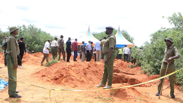 Officers stand near where bodies are being exhumed. Pic: AP