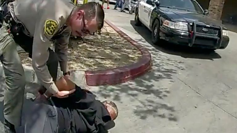 In this image taken from police body camera provided by Los Angeles Sheriff&#39;s office on June 24, 2023, a  Sheriff&#39;s deputies arrested a couple in a grocery store parking lot in Lancaster, Calif. The Los Angeles County sheriff has opened an investigation into two deputies&#39; actions after a bystander&#39;s cellphone footage showed one of them tackling a woman while she filmed her husband being handcuffed in what the scandal-ridden department described as disturbing. (Los Angeles County Sheriff&#39;s Office via AP)