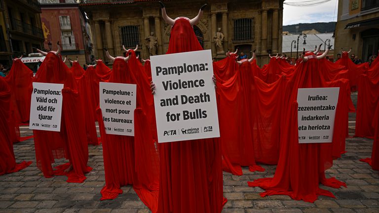 People covered with San Fermin's red color protest against animal cruelty before the start of the San Fermin festival at Plaza del Ayuntamiento square in Pamplona, northern Spain, Wednesday, July 5, 2023. On July 6th, the San Fermin festival will begin and last for nine days where thousands of people will take part in the famous running of the bulls through the old streets of the city. (AP Photo/Alvaro Barrientos)