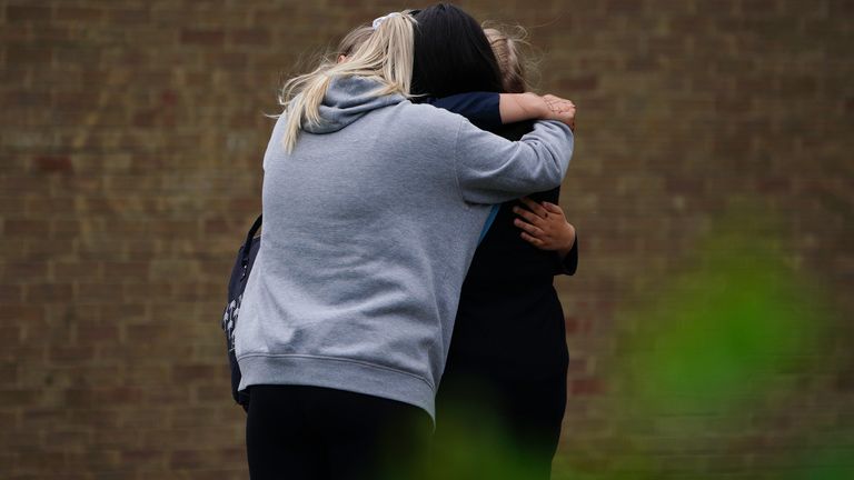 People hugging by the gates of Tewkesbury Academy in Gloucesershire, which was in lock down after a teenage boy was arrested following reports a pupil stabbed a teacher. Picture date: Monday July 10, 2023.

