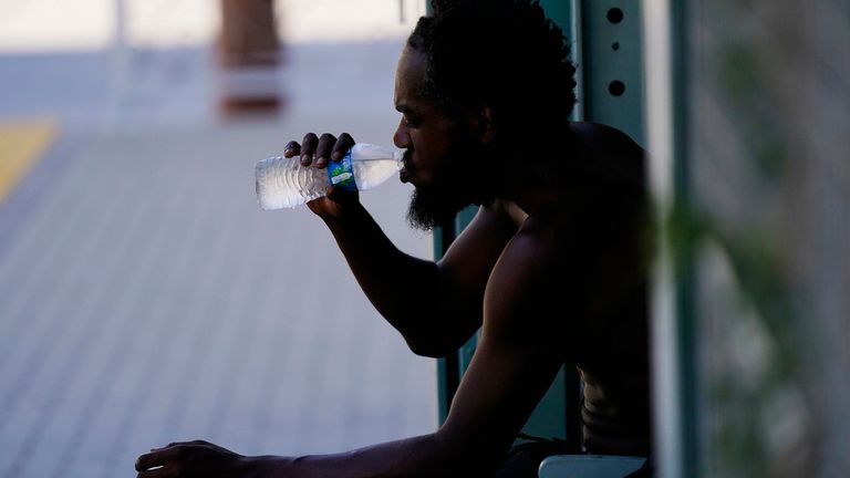 Une personne boit une bouteille d'eau à l'ombre alors que les températures devraient atteindre 119 degrés (48,3 degrés Celsius) le jeudi 20 juillet 2023 à Phoenix.  (AP Photo/Ross D. Franklin)