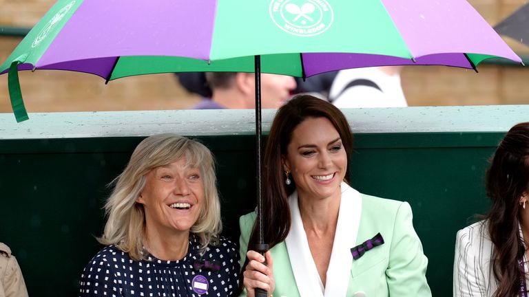 The Princess of Wales alongside Deborah Jevans (left) take shelter from the rain as they watch Katie Boulter in action against Daria Saville on day two of the 2023 Wimbledon Championships  