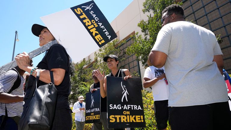 Actor Rosario Dawson, center, attends a rally with striking writers and actors outside Warner Bros. studios in Burbank, Calif. on Friday, July 14, 2023. This marks the first day actors formally joined the picket lines, more than two months after screenwriters began striking in their bid to get better pay and working conditions and have clear guidelines around the use of AI in film and television productions.(AP Photo/Mark J. Terrill)