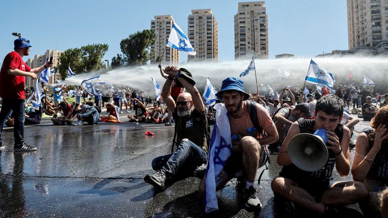 Demonstrators are sprayed with a water cannon during a demonstration against Israeli Prime Minister Benjamin Netanyahu and his nationalist coalition government's judicial overhaul, in Jerusalem July 24, 2023. REUTERS/Ammar Awad
