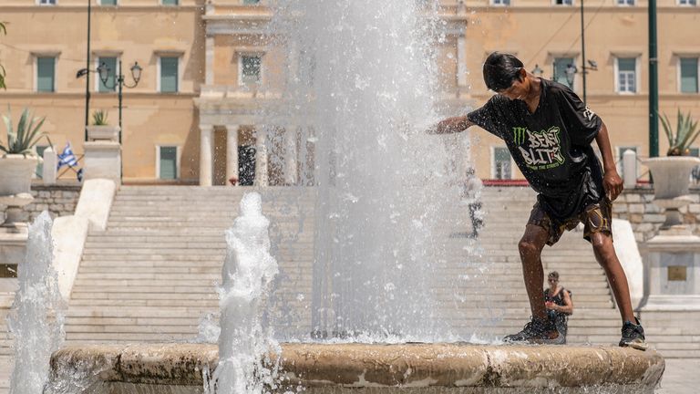 A boy cools himself in a fountain 