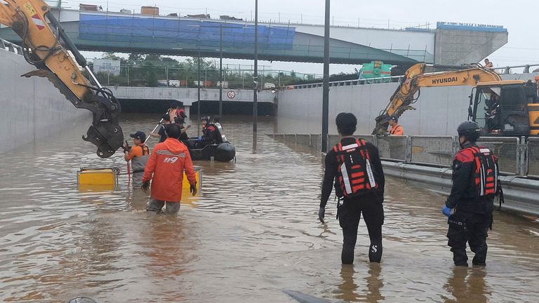 Rescuers search for survivors along a road submerged by floodwaters leading to an underground tunnel in Cheongju, South Korea