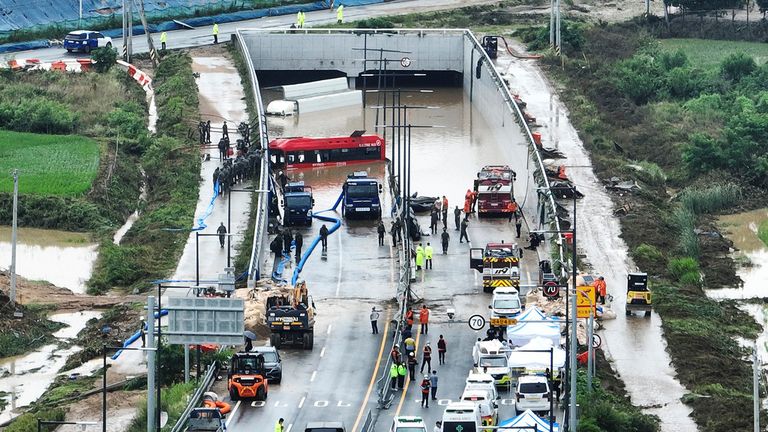 Rescuers work to search for survivors along a road submerged by floodwaters 