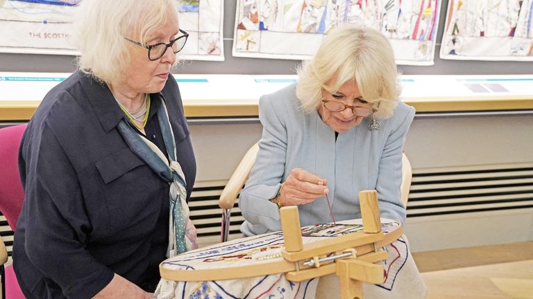 Great Tapestry of Scotland stitcher coordinator Dorie Wilke watches Queen Camilla work on a commemorative tapestry during her visit to The Great Tapestry of Scotland visitor centre in Galashiels, in the Scottish Borders, Scotland, Britain, to mark 10 years since the tapestry was completed and went on display to the public, as part of the first Holyrood Week since King Charles III&#39;s, coronation. Picture date: Thursday July 6, 2023. Andrew Milligan/Pool via REUTERS