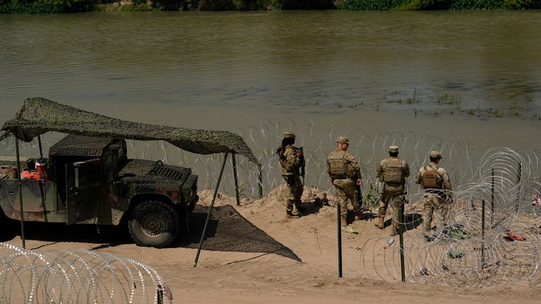 Guardsmen watch as migrants try to cross the Rio Grande from Mexico. Pic: AP