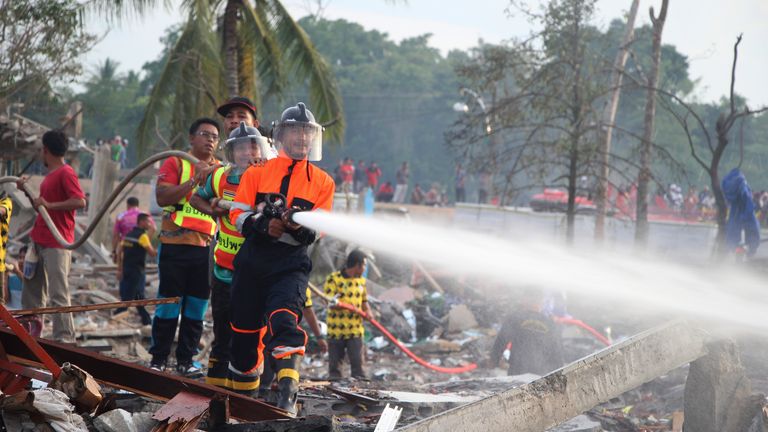 A fireman sprays water after an explosion occured at a firework warehouse in Narathiwat province southern Thailand, Saturday, July 29, 2023. A large explosion at a fireworks warehouse in southern Thailand on Saturday killed at least nine people and wounded scores, officials said. (AP Photo/Kriya Tehtani)
