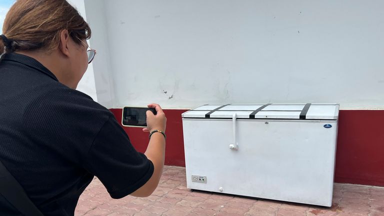 A Thai reporter takes a photo of an empty freezer at the Nong Prue police station